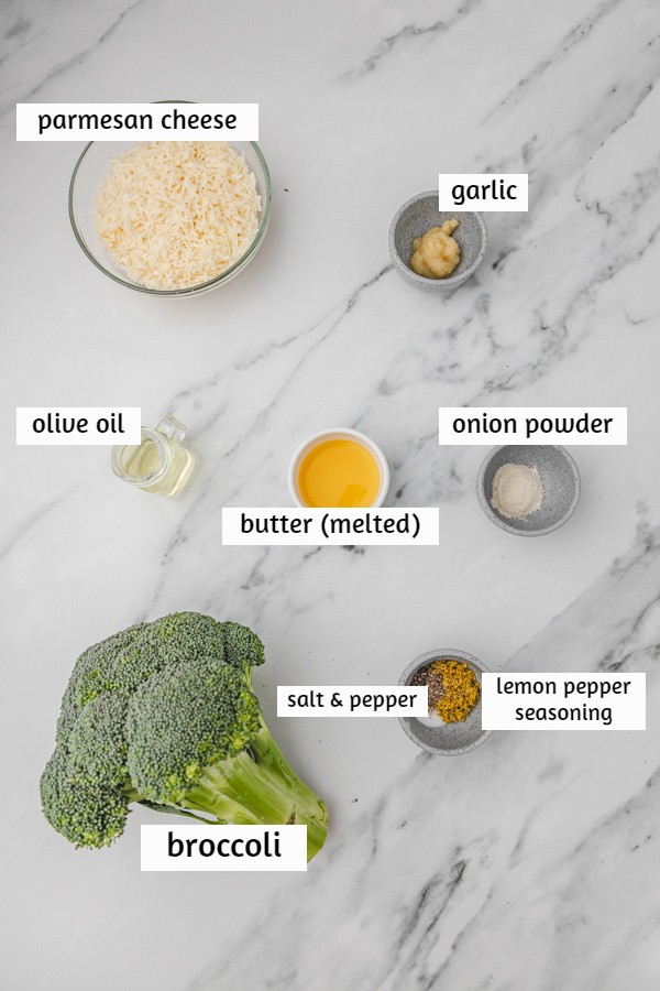 ingredients needed to make roasted broccoli on a white marble surface.
