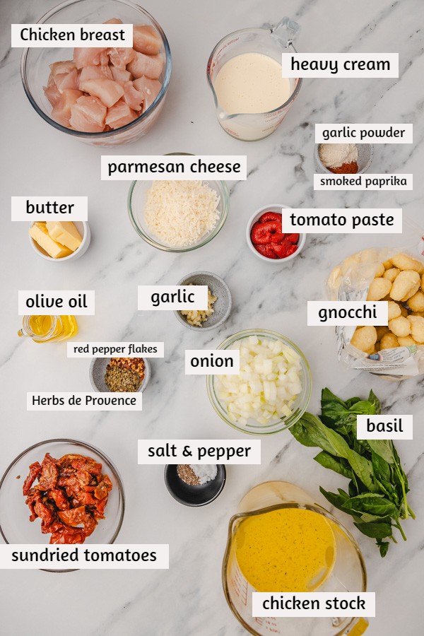ingredients to make creamy gnocchi on a white marble surface.