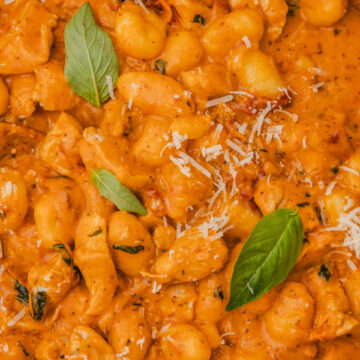 a pot of creamy marry me chicken gnocchi garnished with baby basil leaves.