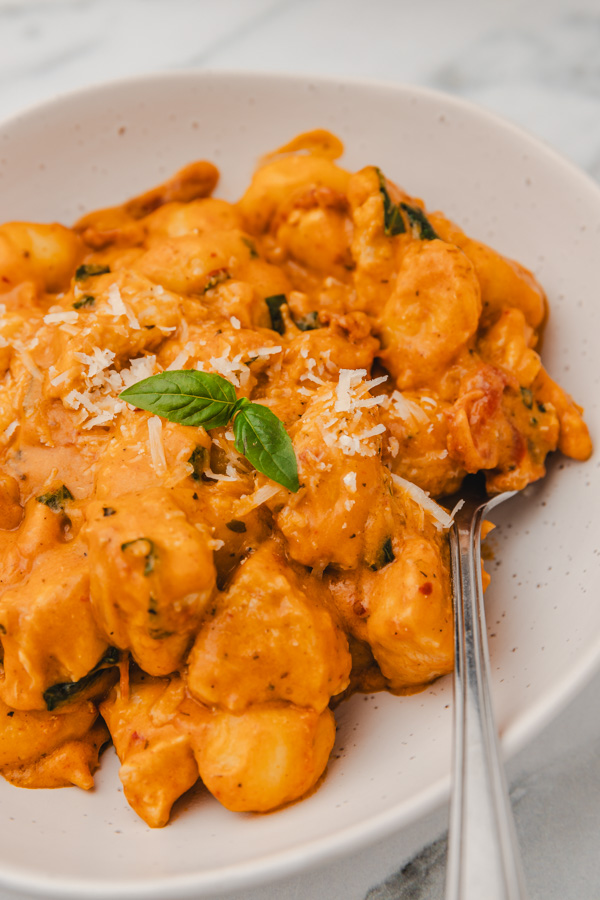 a plate of creamy gnocchi garnished with basil.