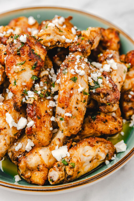 chicken wings garnished with crumbled feta cheese on a plate.