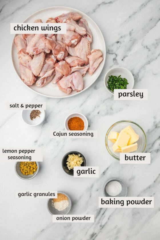 ingredients needed to make garlic butter chicken wings laind on a white marble surface.