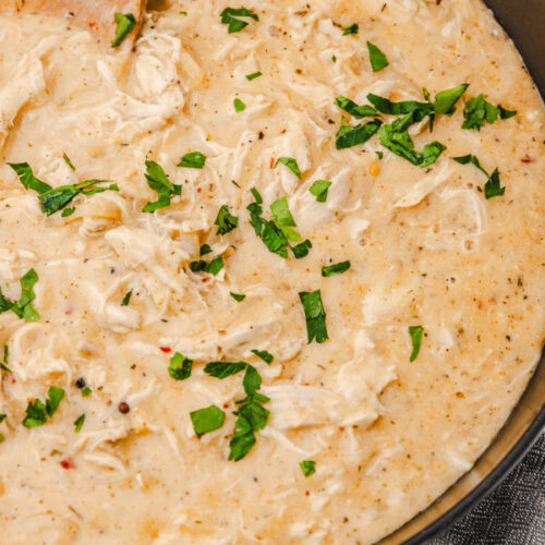chicken gravy garnished with chopped parsley in a skillet.