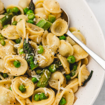 a plate of pasta with asparagus and peas.
